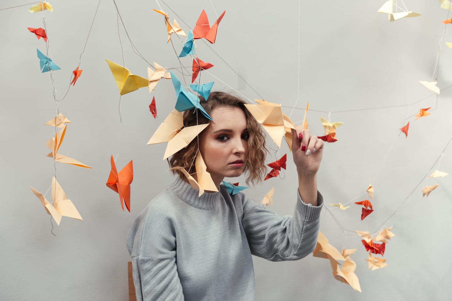 Woman standing among colorful origami