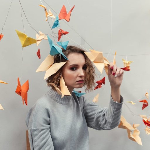 Woman standing among colorful origami